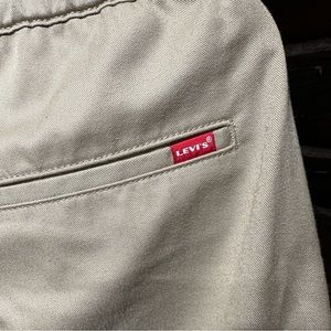 Levi’s khaki’s with elastic waistband, tapered legs, and utility buckle closure.
